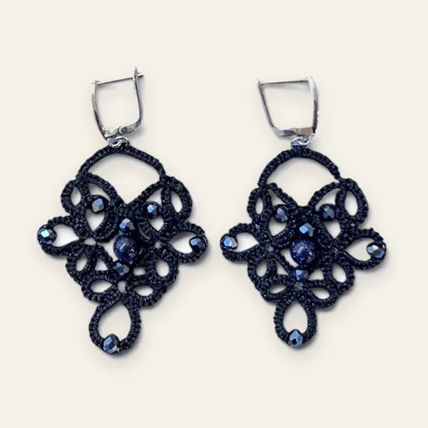 Aros Cielo Nocturno: aros colgantes de encaje frivolité tejido a mano en hilo negro, con cristal facetado azul noche y cuenta central con destellos dorados