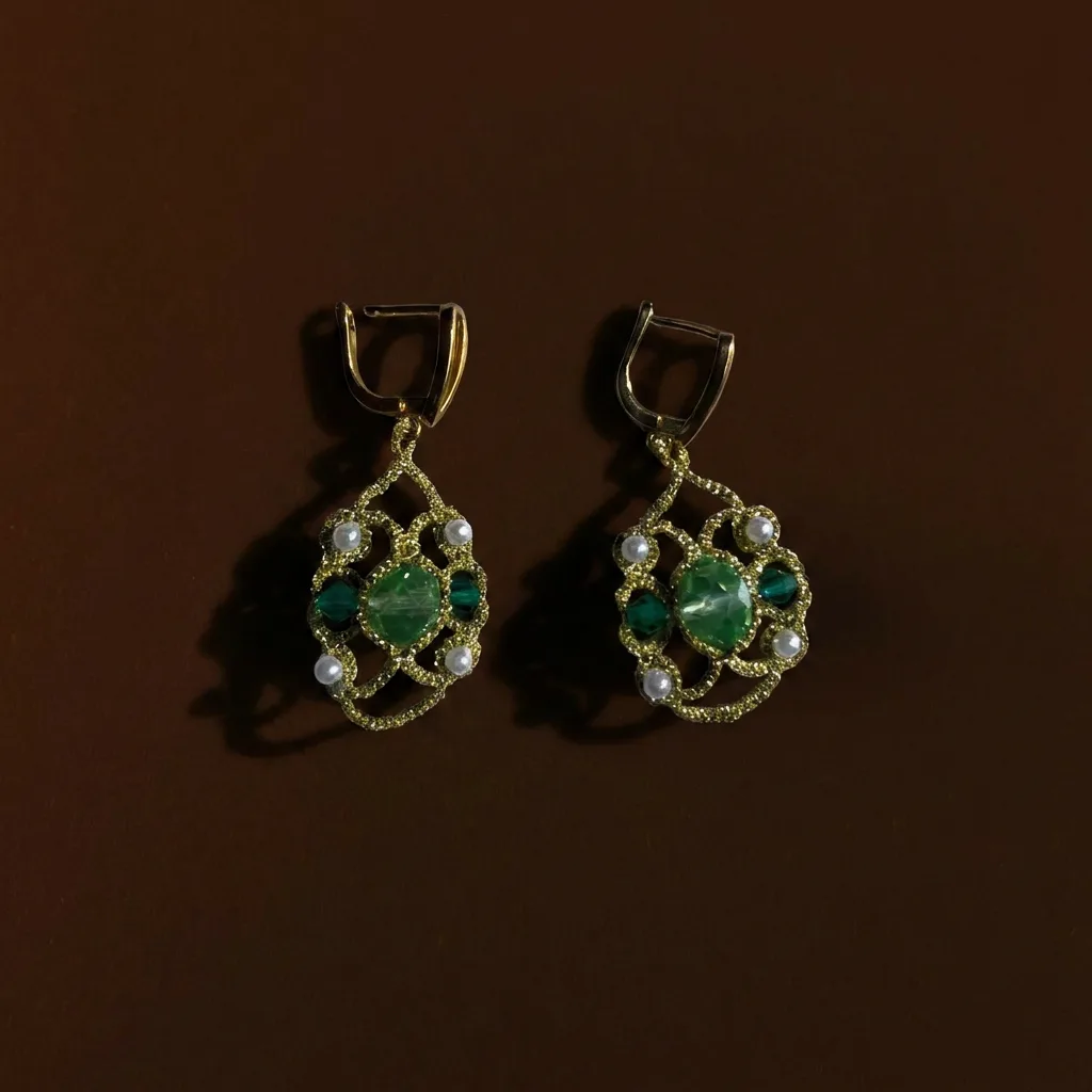Aros Encaje Esmeralda de encaje frivolité dorado con cristales verdes y perlitas, sobre fondo marrón