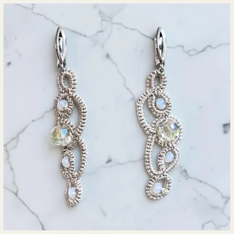 Aros Espuma del Mar: aros largos de encaje frivolité tejido a mano en hilo metalizado plateado, con cuentas opalinas celestes y cristal facetado tornasolado
