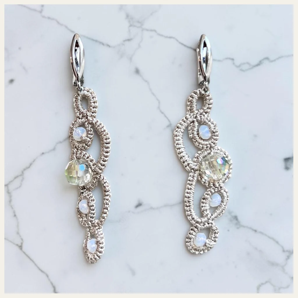 Aros Espuma del Mar: aros largos de encaje frivolité tejido a mano en hilo metalizado plateado, con cuentas opalinas celestes y cristal facetado tornasolado