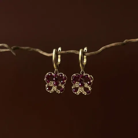 Aros Granate Bordó de encaje frivolité dorado con granates facetados, colgados de una rama sobre fondo marrón