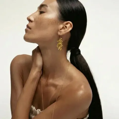 Aros Hojas Doradas de encaje frivolité dorado puestos en la oreja de una modelo