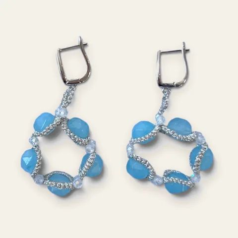 Aros Laguna Azul: aros medianos de encaje frivolité tejido a mano en hilo metalizado plateado, con cristal facetado celeste esmerilado y cuentas transparentes