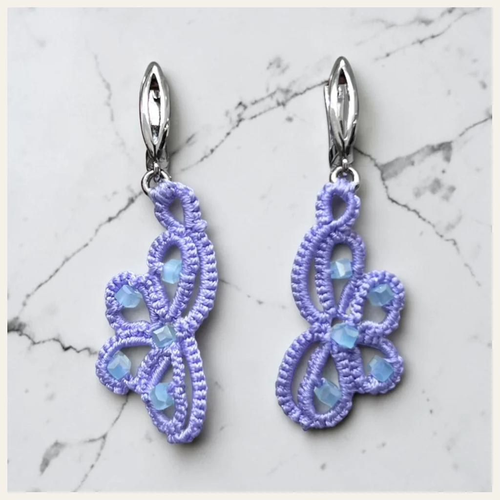 Aros Mariposa de Lavanda: aros medios de encaje frivolité tejido a mano en hilo lila mate, sin hebra metalizada, con cristal facetado color celeste opalino