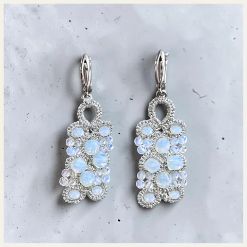 Aros Rocío de Nieve: aros medianos de encaje frivolité tejido a mano en hilo metalizado plateado, con cuentas opalinas blanco lechoso y mostacillas transparentes con reflejo celeste