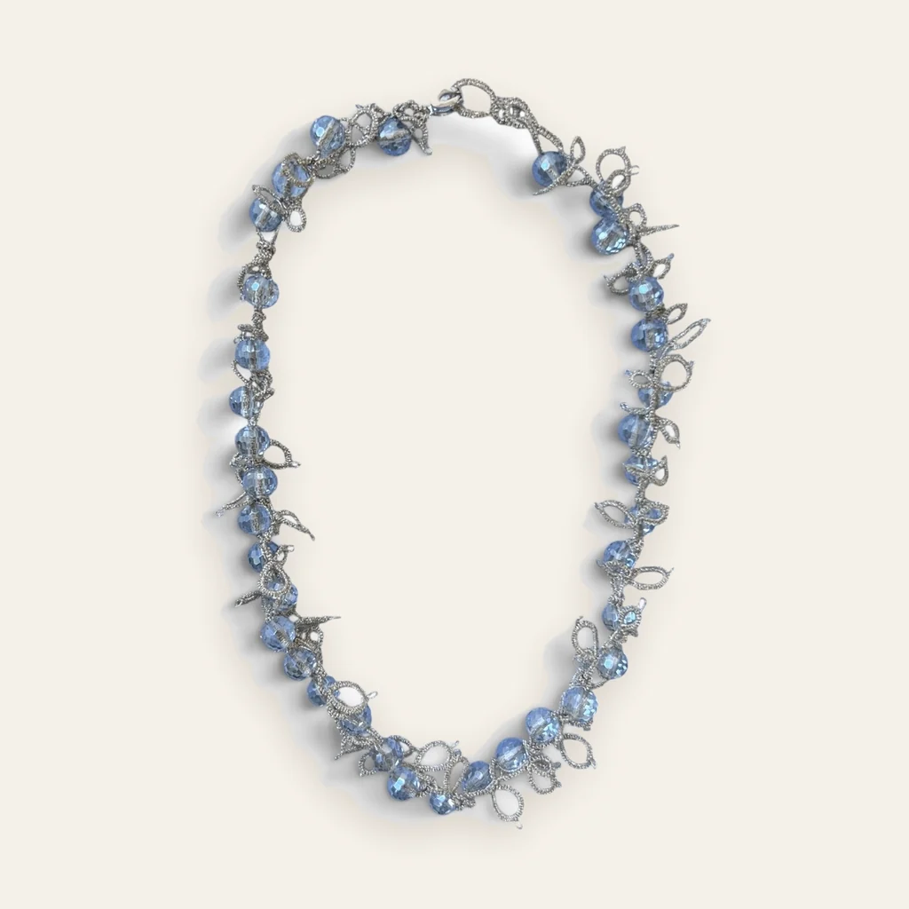 Collar Brisa Helada: gargantilla de encaje frivolité tejido a mano en hilo metalizado plateado, con cristales facetados color celeste