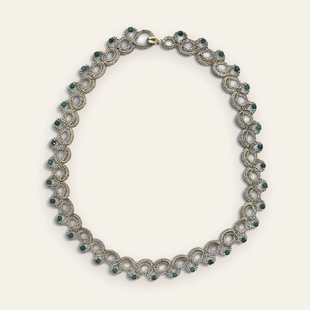 Collar Gota de Esmeralda: gargantilla de encaje frivolité tejido a mano en hilo metalizado color champán, con cristales facetados color verde esmeralda