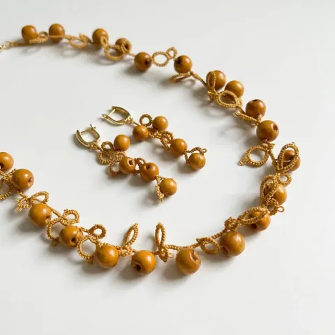 Conjunto Jengibre de encaje frivolité: collar y aros con cuentas ocre sobre fondo blanco