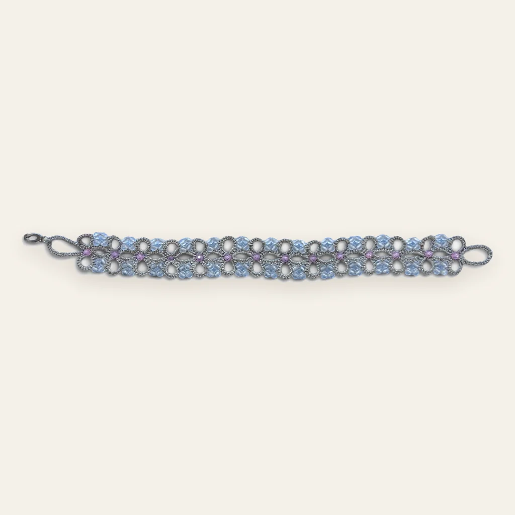 Pulsera Cerezos en Flor: pulsera ancha de encaje frivolité tejido a mano en hilo metalizado gris plata, con cristales facetados celeste, blanco hielo y rosa lila