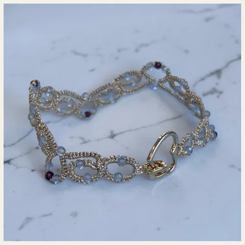 Pulsera Corazón Dorado: pulsera de eslabones de encaje frivolité tejido a mano en hilo metalizado dorado claro, con cristales facetados blanco hielo y color granate