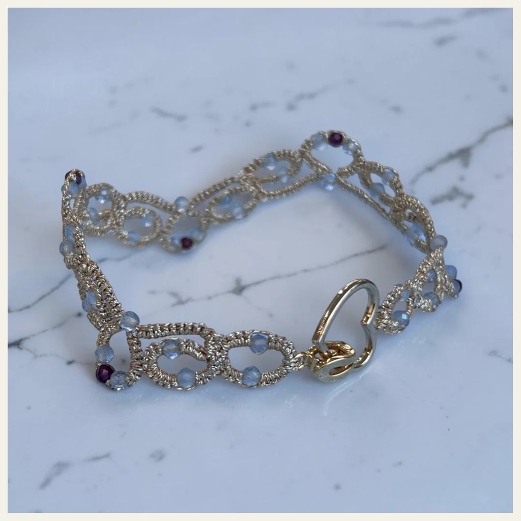Pulsera Corazón Dorado: pulsera de eslabones de encaje frivolité tejido a mano en hilo metalizado dorado claro, con cristales facetados blanco hielo y color granate