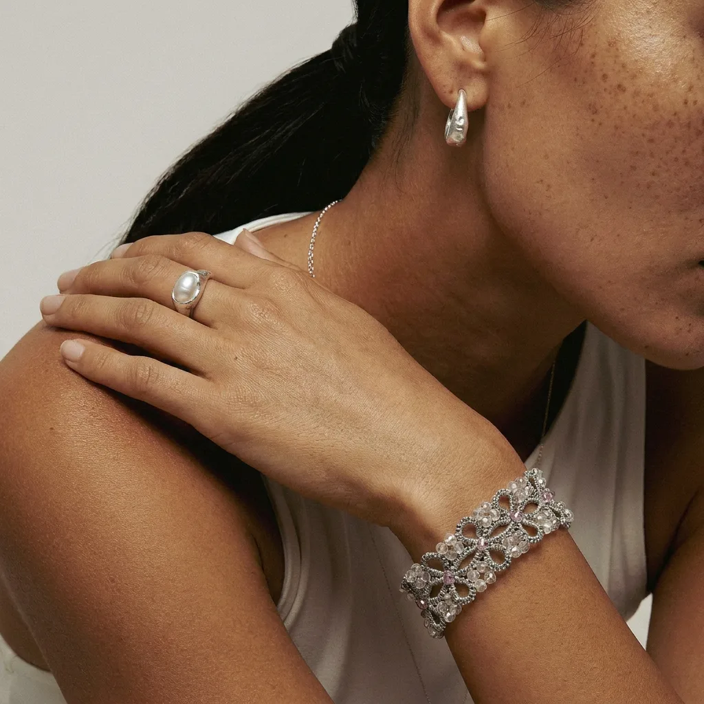 Pulsera Pétalos Plata de encaje frivolité con cuentas cristalinas, puesta en la muñeca de una modelo
